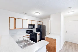 Kitchen with white cabinets and countertops, black appliances and stainless steel double sink