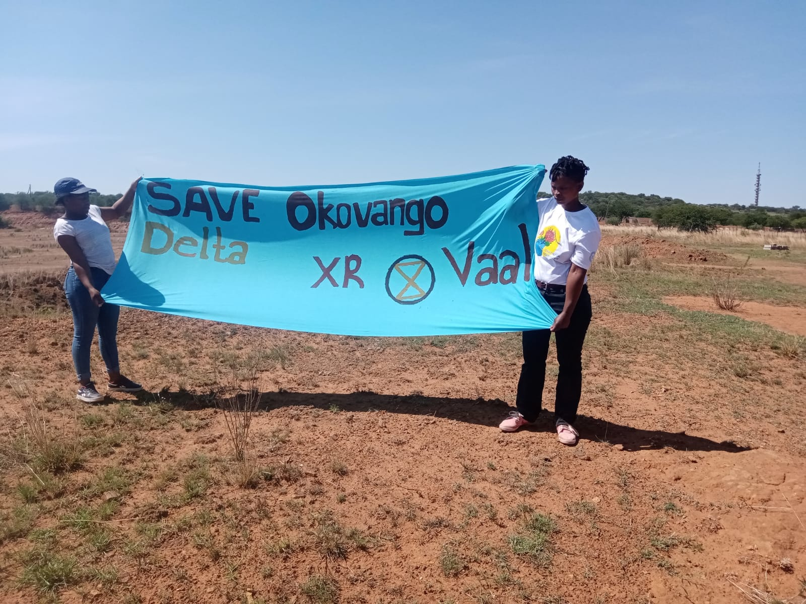 Two women rebels hold a banner that says save Okovango Delta