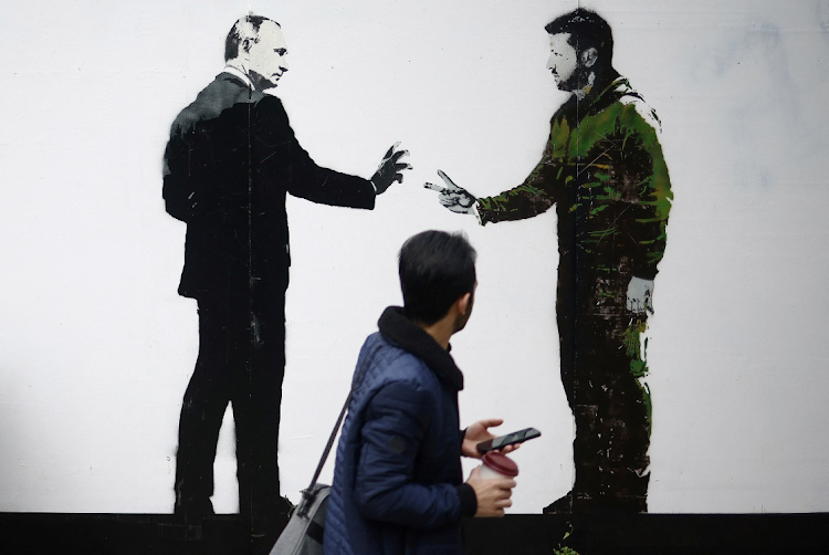 A man walks past a mural by street artist Loretto depicting Russian President Vladimir Putin and Ukrainian President Volodymyr Zelensky, in London, October 4, 2022. Picture: REUTERS/Henry Nicholls