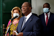 Ivory Coast President Alassane Ouattara speaks next to his wife Dominique after casting their votes at a polling station during the presidential election in Abidjan, Ivory Coast October 31, 2020. 