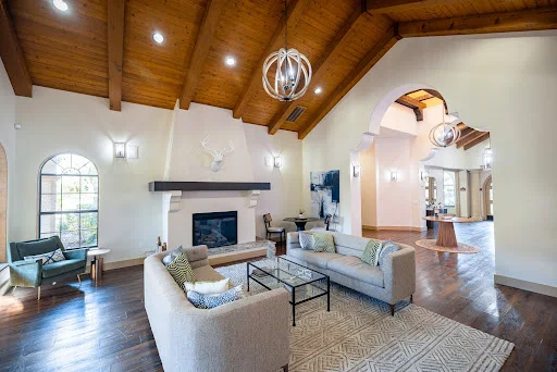 Clubhouse lounge area with fireplace with mantel, two gray couches with accent pillows, and architectural details