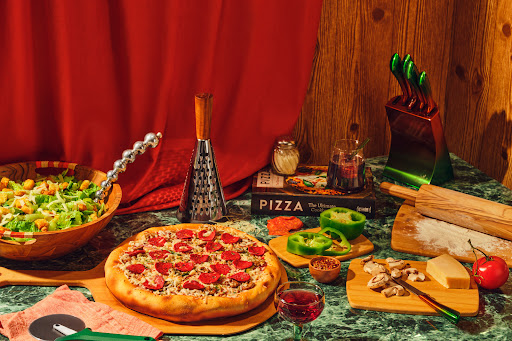 A green counter filled with pizza ingredients and a pizza-shaped cake.