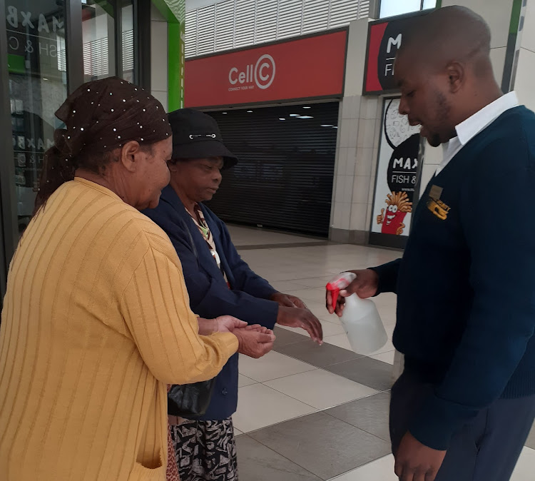 Sassa beneficiaries get sanitised before getting into the shop to collect their money at Nkomo village shopping center.