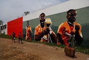 People pass in front of graffiti showing the Ivory Coast team winners of the 2015 Africa Cup of Nations, as Ivory Coast gears up to host the Africa Cup of Nations which begins on Saturday