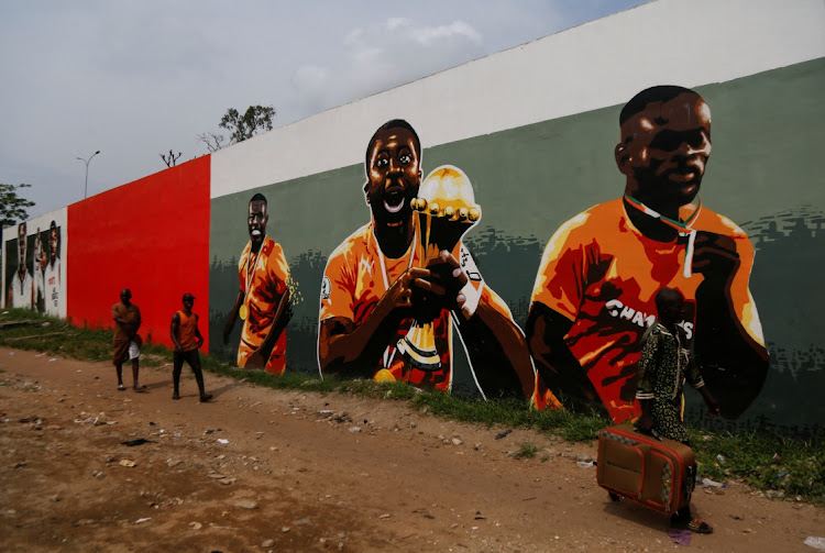 People pass in front of graffiti showing the Ivory Coast team winners of the 2015 Africa Cup of Nations, as Ivory Coast gears up to host the Africa Cup of Nations which begins on Saturday