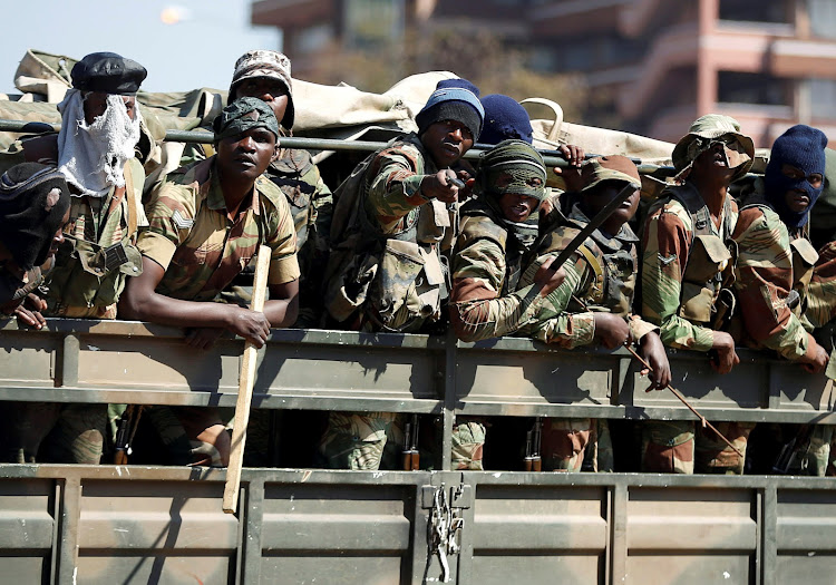 Members of the military gesture to the photographer as they patrol the streets of the capital Harare, Zimbabwe, August 2, 2018.