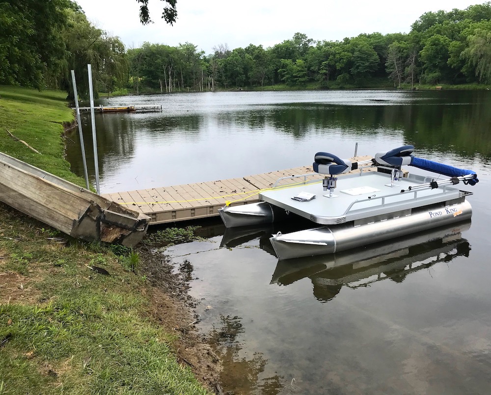 Pontoon boat next to dock in pond