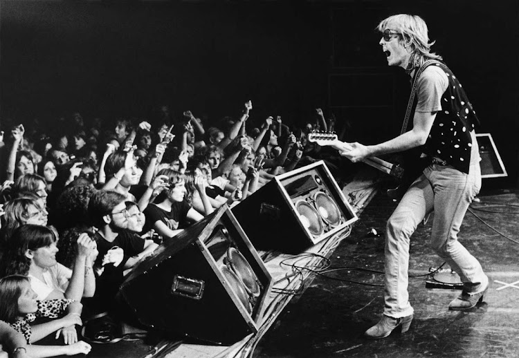 Singer Tom Petty, backed by his band, The Heartbreakers, prances onstage during a 1980 Santa Cruz, California, concert at the Civic Auditorium. Petty was born on October 20, 1950, in Florida. He died at age 66 of cardiac arrest on October 2, 2017, in California.