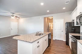 Kitchen island with white cabinets, granite countertops, an a sink overlooking the living area