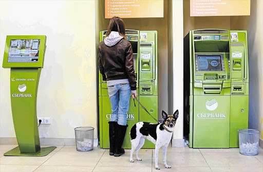 PANIC: A woman with a dog uses an automated teller machine at a branch of Sberbank in Stavropol, Russia, which is on the brink of a currency crisis on the back of Western sanctions and cheap oil