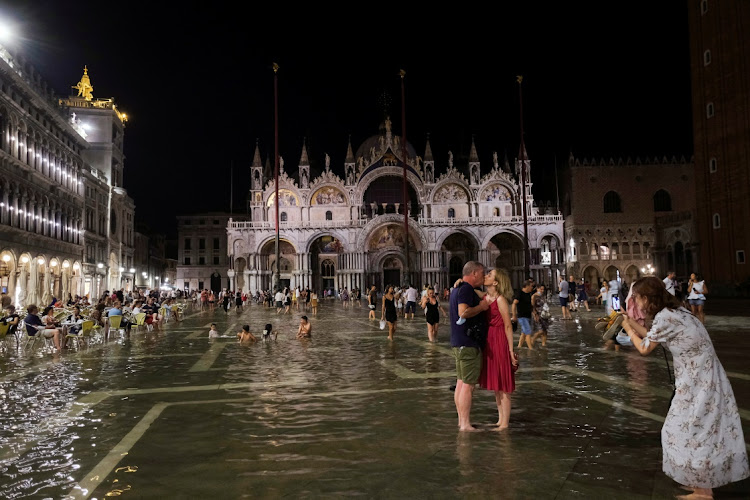 People walk in a flooded St. Mark's Square during an exceptional high water in Venice, Italy August 8, 2021. Picture taken August 8, 2021.
