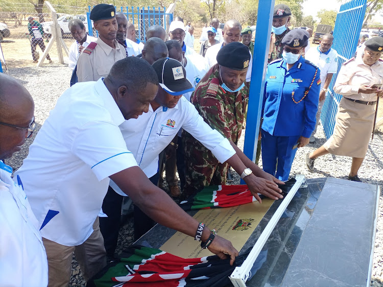 The administrative director at the Ministry of Water Douglas Mutai unveils the plague to officially commission the Maliku- Kavisuni borehole on Tuesday, March 22.