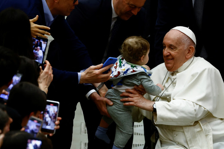 Pope Francis holds a child during a meeting with the faithful of parishes from Rho at the Vatican, March 25 2023.