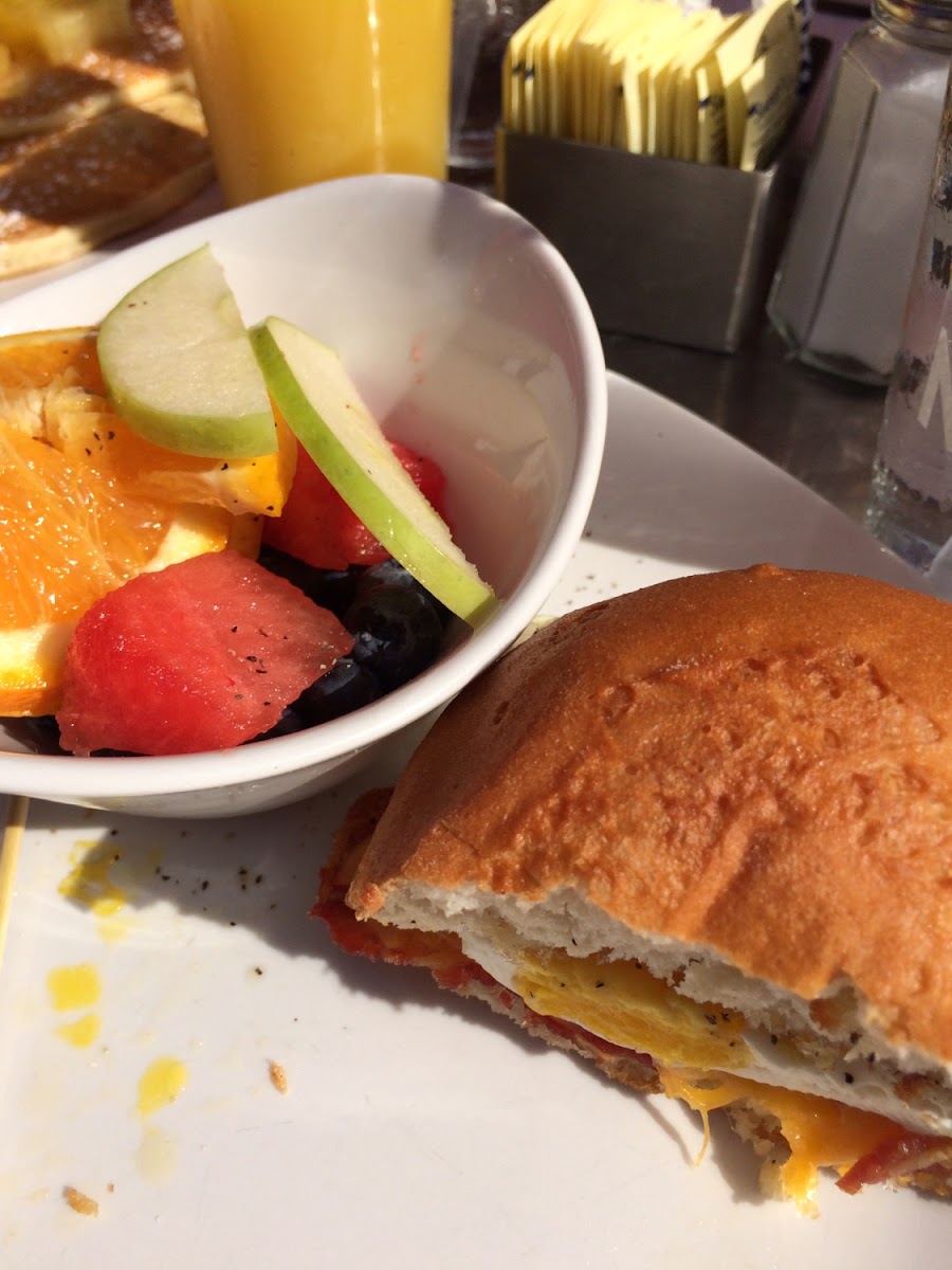 Gluten free roll with the egg sandwich from the menu. Included, bacon, cheddar cheese, and a fried egg. Side item was fruit salad.