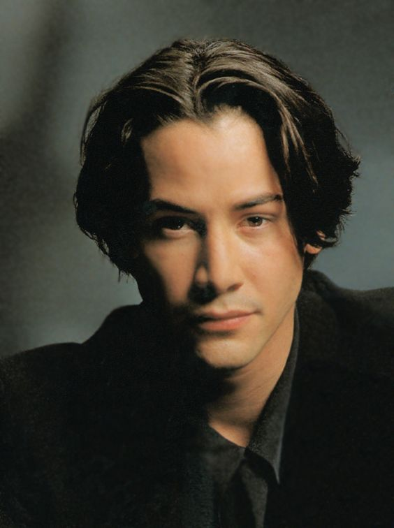 A picture showing Keanu Reeves rocking the middle part hairstyle