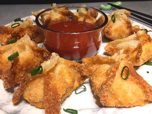 A few delicious crab rangoon with a dipping sauce