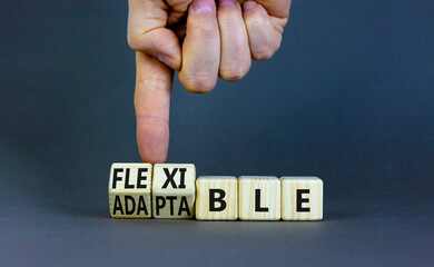 Adaptable or flexible symbol. Businessman turns wooden cubes and changes the word Adaptable to Flexible. Beautiful grey table grey background, copy space. Business, adaptable or flexible concept.