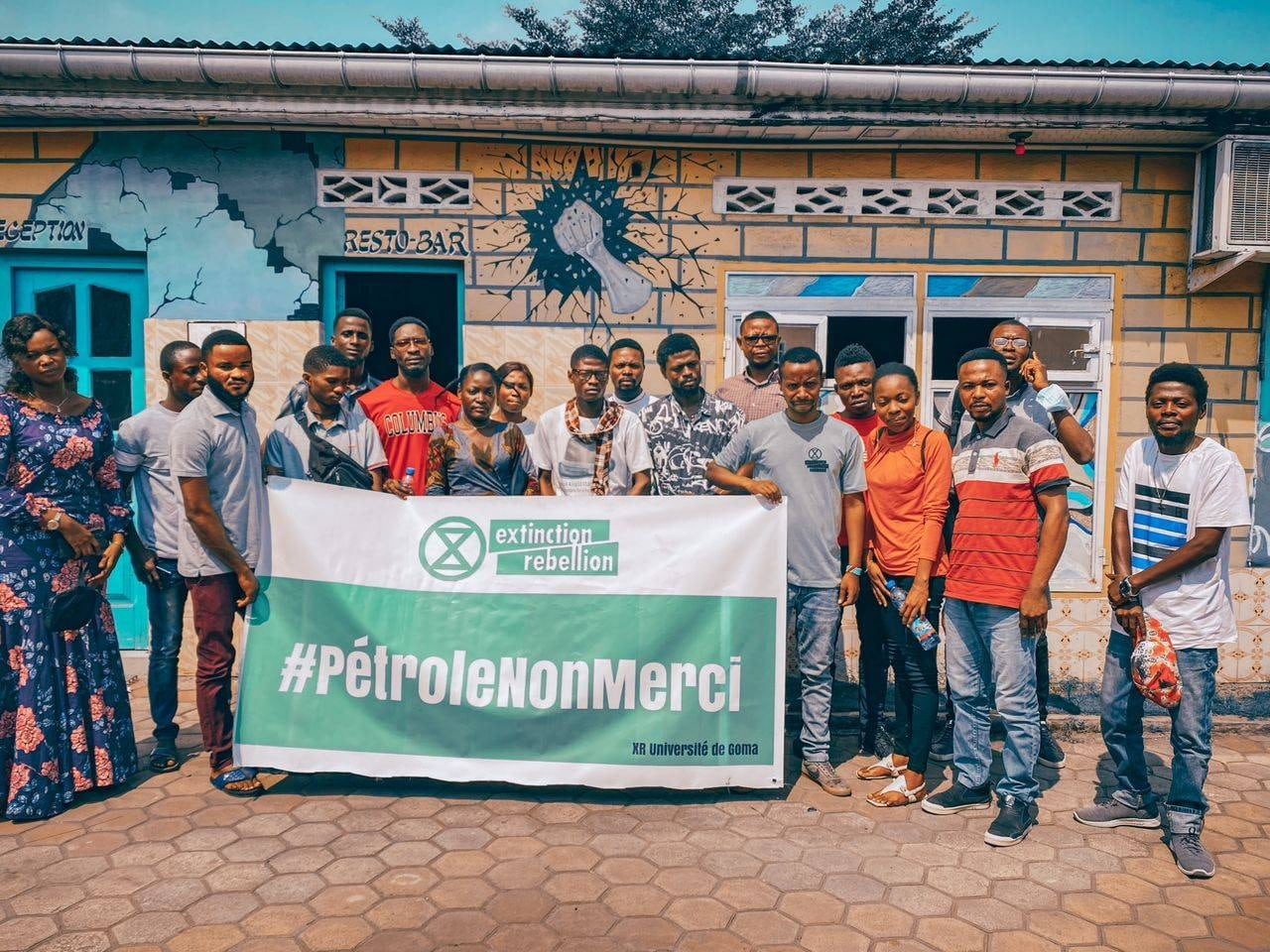 Rebels hold a Petrol Non Merci banner outside a community building in Moanda