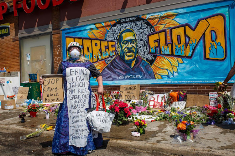 A protester stands near a memorial following a day of demonstrations in a call for justice for George Floyd, who died while in the custody of the Minneapolis police in Minnesota, US