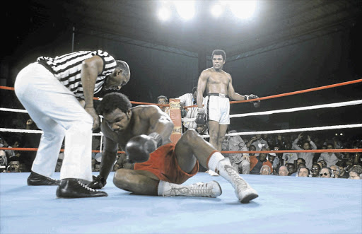 FLOORED: George Foreman tries to get off the canvas as referee Zack Clayton checks on him during his fight against Muhammad Ali, in Kinshasa, Zaire, in October 1974