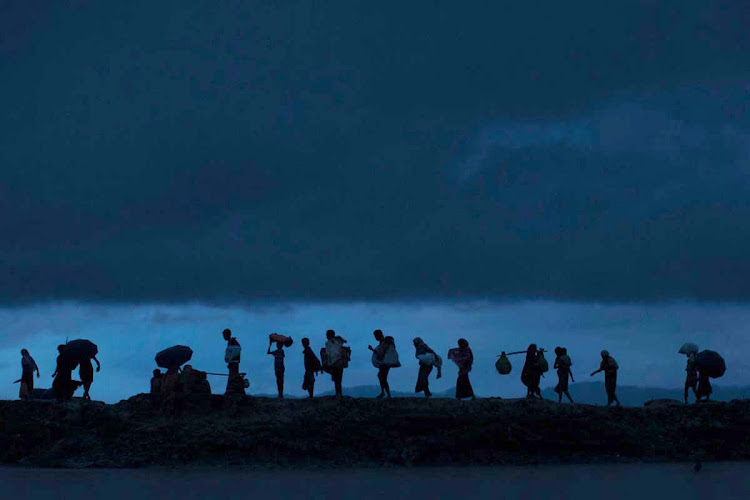 Rohingya refugees walk across Paddy fields at dusk after crossing the border from Myanmar on September 09, 2017 in Gundum, Bangladesh. Recent reports have suggested that around 290,000 Rohingya have fled Myanmar. Those who left have spoken of violence erupting in Rakhine state, when the country's security forces allegedly launched an operation against the Rohingya Muslim community.