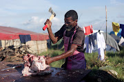 A man prepares a cow head for cooking where thousands of Ebuhleni faction of the Nazareth Baptist Church members are gathered for their annual pilgrimage. 