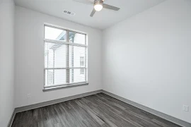 Bedroom with wood-inspired flooring, light walls, and ceiling fan