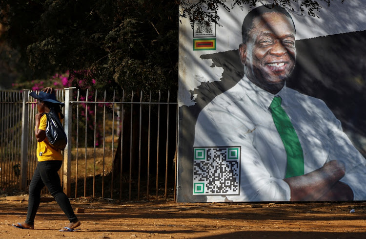 A woman walks past a billboard with a face of Zimbabwe President Emmerson Mnangagwa in the capital Harare, in Zimbabwe, August 22, 2023.