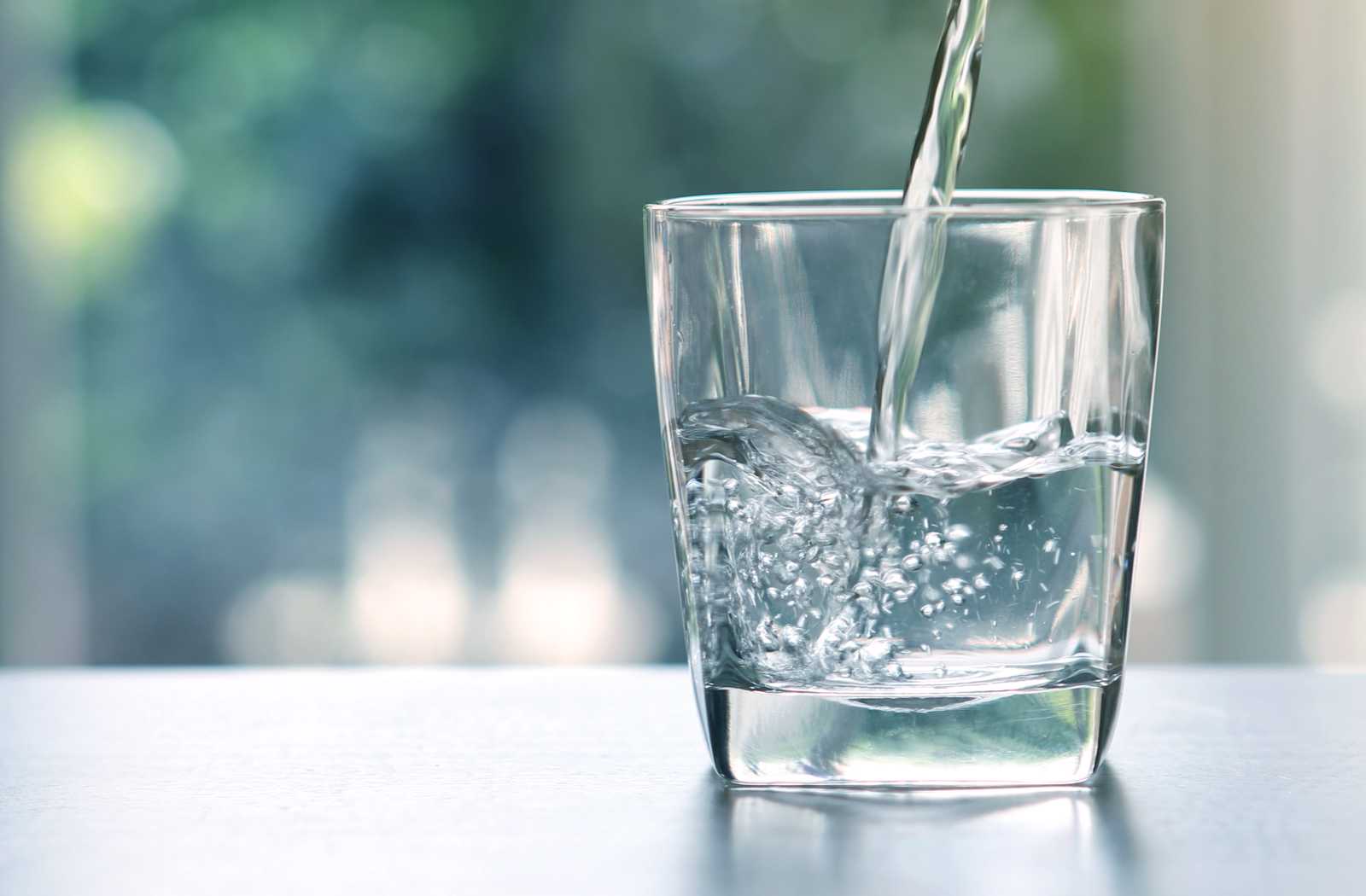 Glass of water being poured against soft lit background