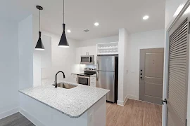 Kitchen with peninsula island featuring matte black pendant lighting, granite countertops, and upscale finishes