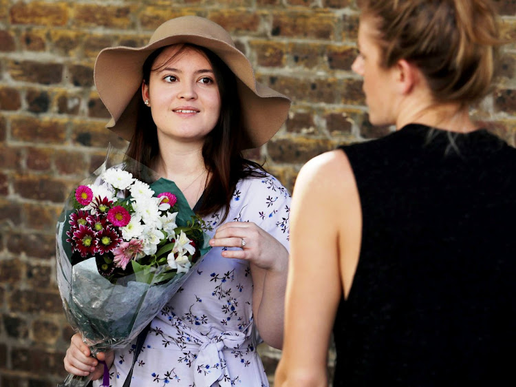 Catherine Arzul waits with her flowers outside the Desmond and Leah Tutu Legacy Foundation on Wednesday.