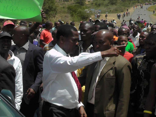 END OF THE ROAD:Council of Governors chairman Peter Munya (in red tie) calms pro- testers at Maili Sita on the Nanyuki-Meru road on Monday. The protesters complained of extraction of water in major rivers by farms in the area