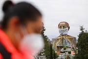 A banner fashioned to resemble a giant protective mask is placed on a monument of Benito Juarez, as a message to the community to fight against the spread of the coronavirus disease (COVID-19), in the Iztapalapa neighbourhood, one of the highly contagious zones, in Mexico City, Mexico, August 13, 2020. 