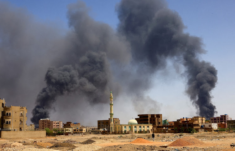 A man walks while smoke rises above buildings after aerial bombardment, during clashes between the paramilitary Rapid Support Forces and the army in Khartoum North, Sudan, on May 1 2023. File Photo