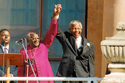 The late Anglican archbishop Desmond Tutu and Nelson Mandela salute the crowd from the balcony of the Cape Town City Hall.