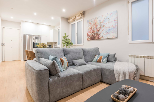 Modern living room with grey sofa and open kitchen in this luxury apartment / penthouse for sale in Madrid ($971,660 - 64 m²)