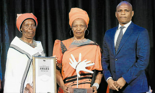 TEARS OF JOY: Nonkoliseko and Zinziswa Tofu accept an award on behalf of their late mother, Mama Tofu, from economic development, environmental affairs and tourism MEC Sakhumzi Somyo. Tofu was remembered at the Lilizela awards held at The Venue@Hemingways on Thursday night. Picture: SINO MAJANGAZA