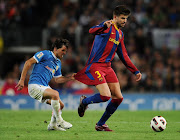 Pablo Piatti (L) of Almeria tries to stop Gerard Pique of Barcelona by holding on to his shorts during the La Liga match at the Camp Nou stadium on April 9, 2011 in Barcelona, Spain