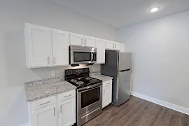 Kitchen with white cabinets, stone countertops, and stainless steel appliances 