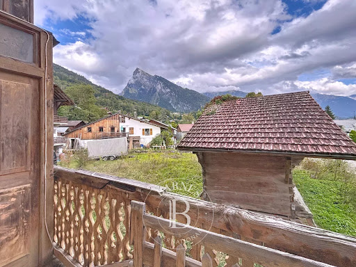 Mountain view from wooden balcony in this luxury farmhouse for sale in Samoens ($721,203)