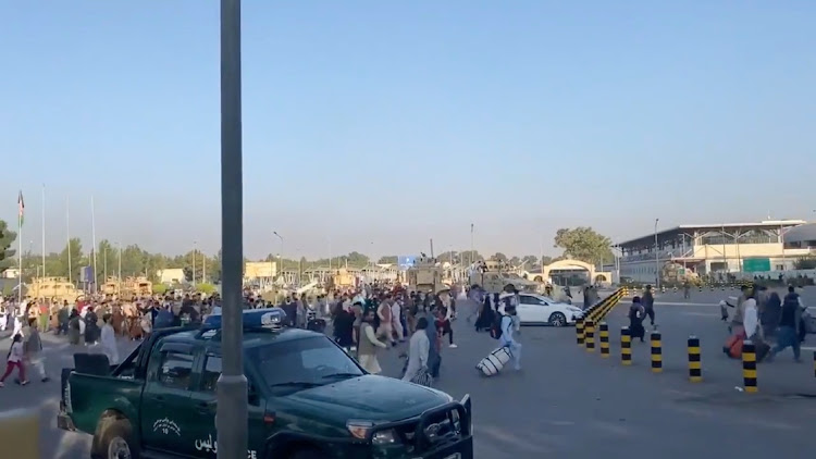 A horde of people run towards the Kabul Airport Terminal, after Taliban insurgents took control of the presidential palace in Kabul, on August 16, 2021