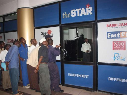 Members of the public peep through Radio Africa offices Mombasa to follow the live proceedings of the naming of the six suspected mastermind of the post election violence announced by Prosecutor Luis Moreno Ocampo. photo/file