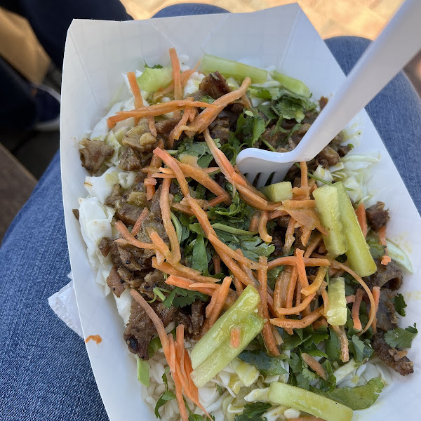 Cabbage and rice bowl with lemongrass pork, pickled carrots, cucumber, cilantro, and a cilantro-lime dressing