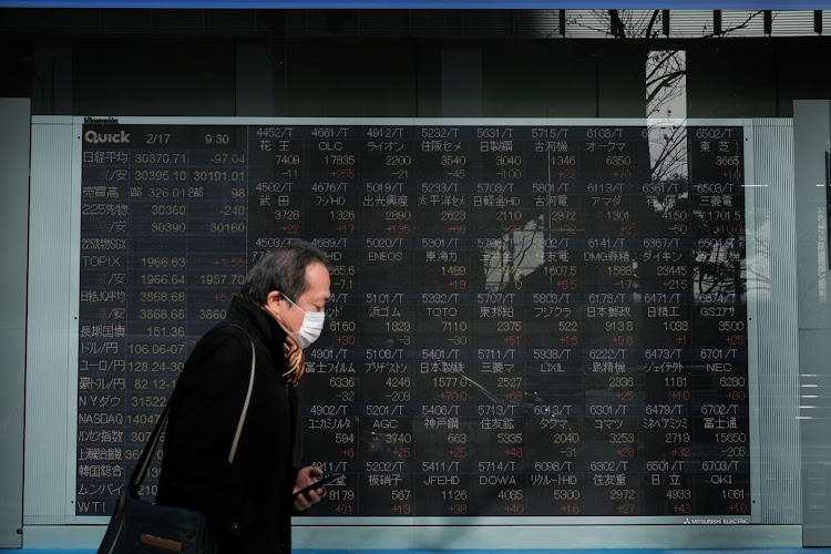 A pedestrian wearing a protective mask walks past an electronic stock board outside a securities firm in Tokyo, Japan. Picture: BLOOMBERG/SOICHIRO KORIYAMA