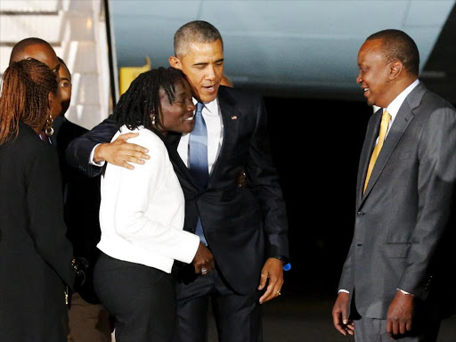 U.S. President Barack Obama embraces his half-sister Auma Obama and is greeted by Kenya's President Uhuru Kenyatta as he arrives at Jomo Kenyatta International Airport in Nairobi/FILE