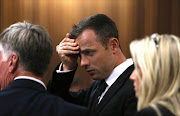 Oscar Pistorius laughs gestures during his court appearance on the third day of his trial at the North Gauteng High Court in Pretoria, on March 5, 2014. Three days into the athlete's trial for his lover's premeditated killing, the state called Pistorius' friend Kevin Lerena to testify about one of three other charge listens to his legal team against Pistorius. AFP PHOTO/ POOL/ ALON SKUYI