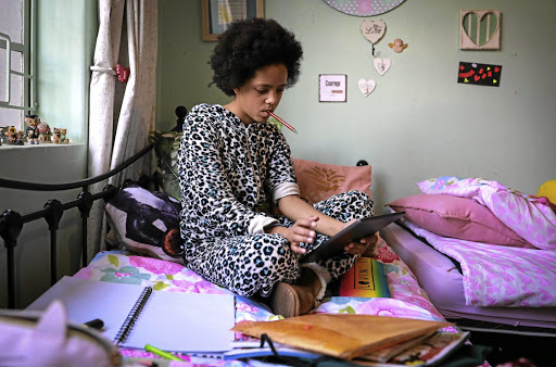 Grade 8 pupil Kia van Oerle on her bed in her pyjamas listening to a teacher's lesson on her iPad. Some schools have turned to virtual teaching as the country battles to contain the spread of Covid-19.