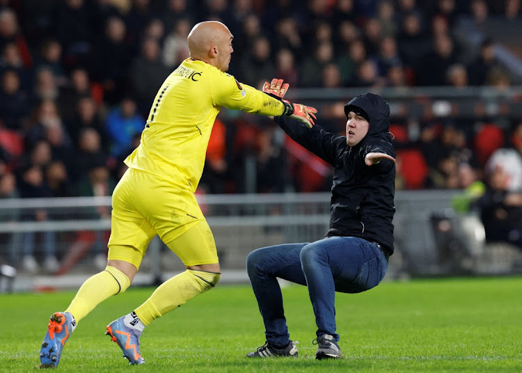 A pitch invader clashes with Sevilla's Marko Dmitrovic.