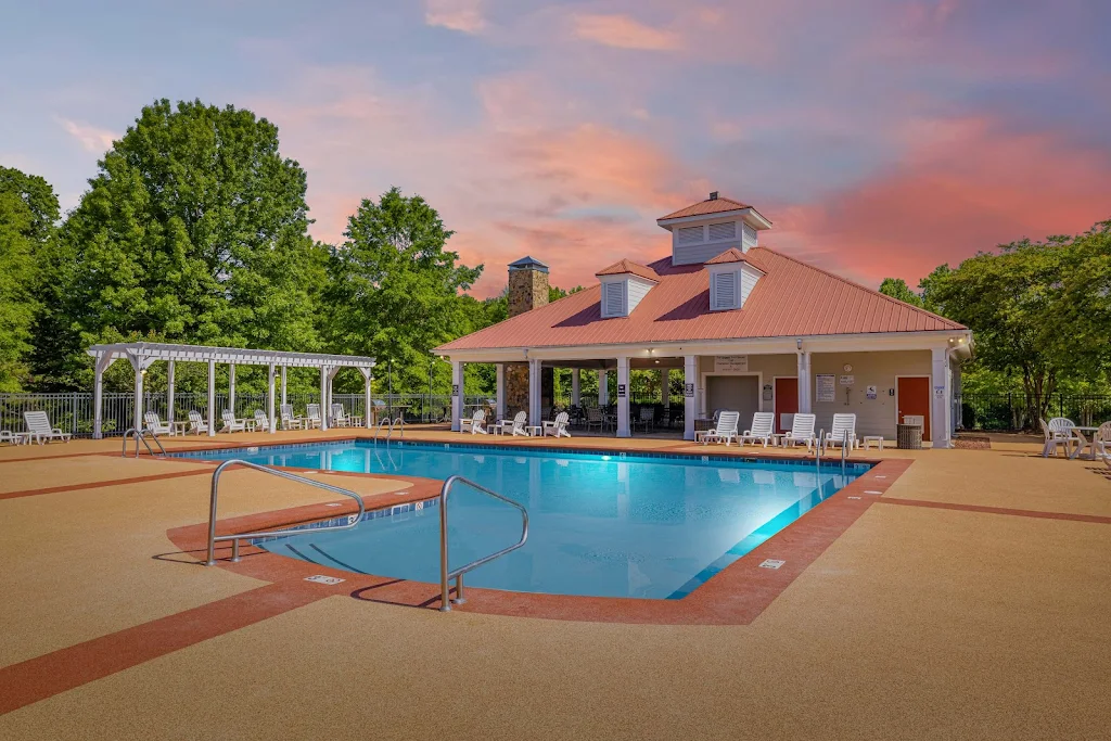 Ashbury Square Apartments community pool at dusk with lounge chairs surrounding and pergolas