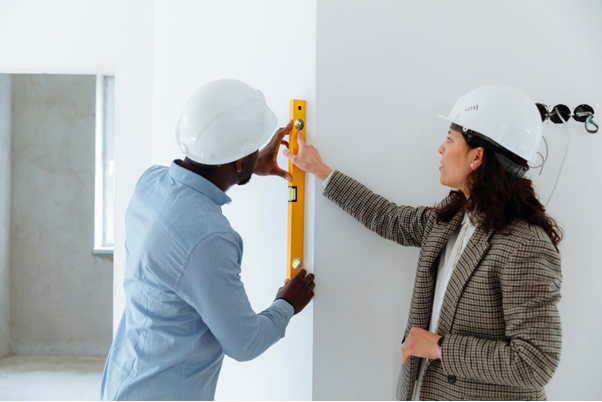 Man and woman measuring a wall.